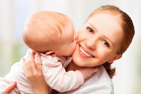 Un bebé besa a su madre mientras esta lo sostiene en brazos