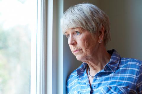 Mujer mayor deprimida mirando por la ventana