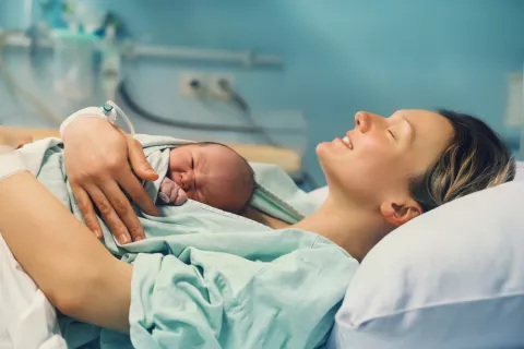 Las mujeres embarazadas reciben células fetales que permanecen en su cuerpo y su cerebro Mujer en el hospital con su recién nacido en brazos