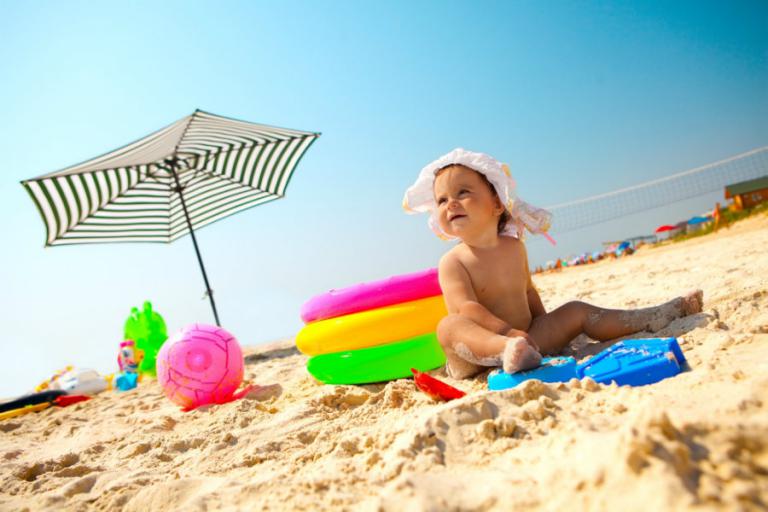 Un bebé juega en la arena de la playa