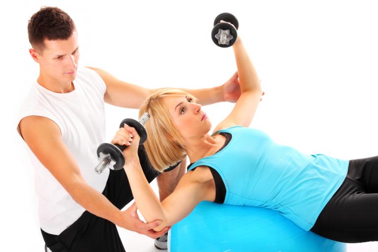 Entrenador personal ayuda a hacer bien un ejercicio a una mujer
