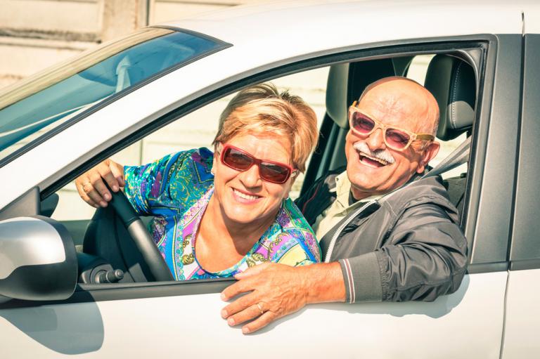 Una pareja mayor sonríe en su coche