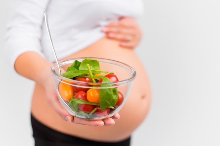 Mujer embarazada con un bol de verduras