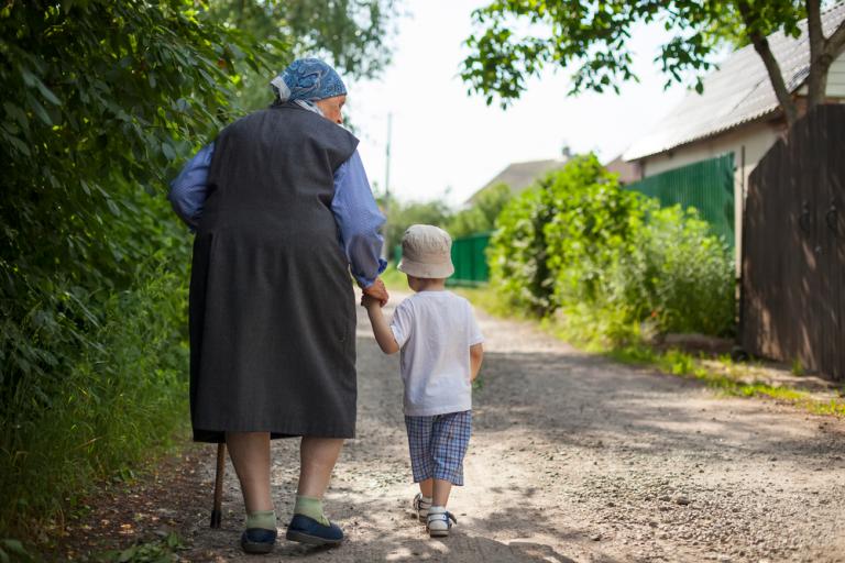 Una anciana pasea dando la mano a un niño pequeño