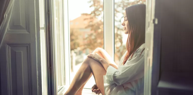 Mujer en la ventana disfrutando de la soledad