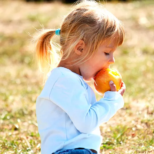 Niña tomando fruta para evitar la encopresis