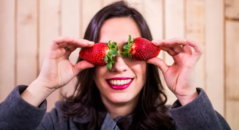 Mujer con unas fresas sobre los ojos