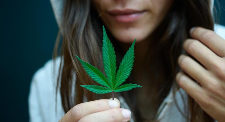 Chica con una hoja de cannabis