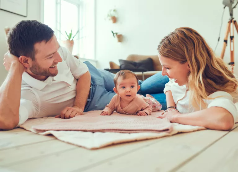 Padres con su bebé en una manta para prevenir el síndrome del bebé retenido