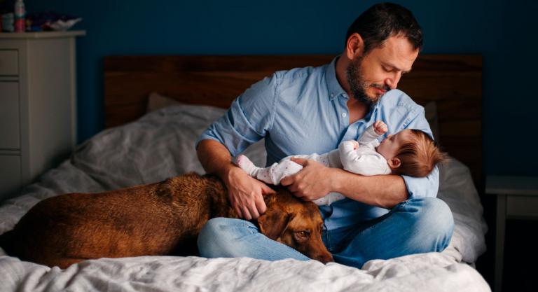 Padre con su hijo y mascota en la cama