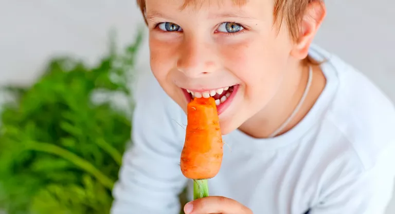 Niño comiendo una zanahoria