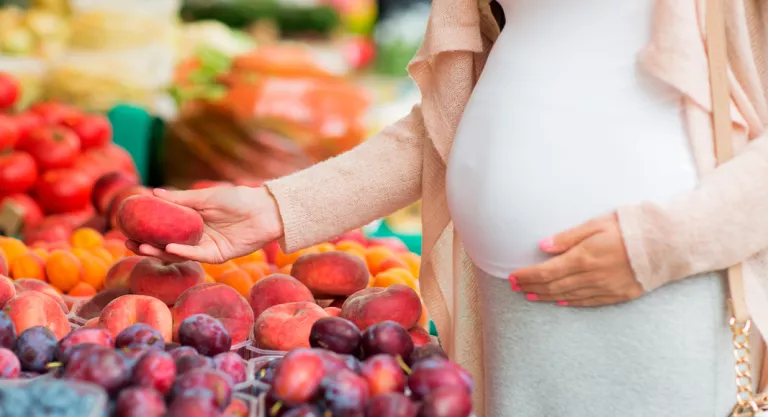 Mujer embarazada tomando fruta