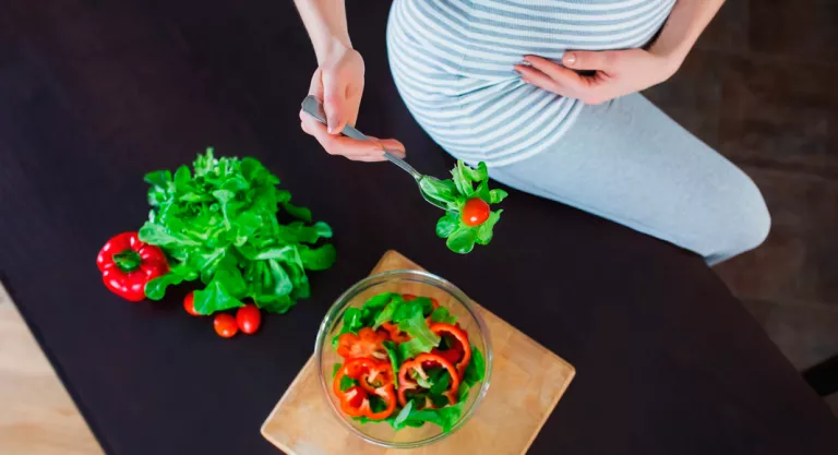 Mujer embarazada tomando una ensalada