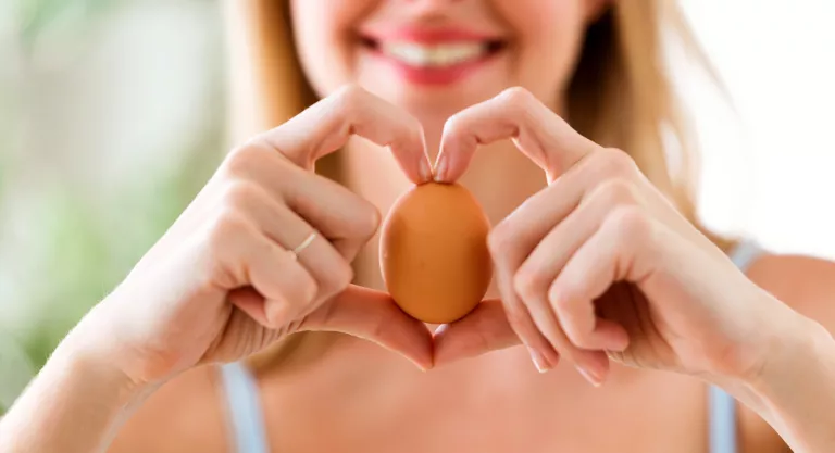 Mujer con un huevo en las manos formando un corazón