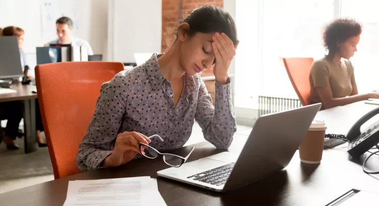 Mujer sufriendo migraña en el trabajo