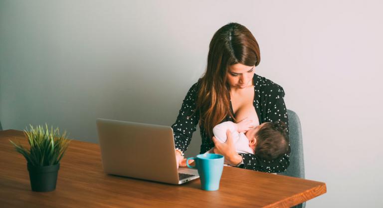 Mujer dando el pecho a su bebé mientras está trabajando
