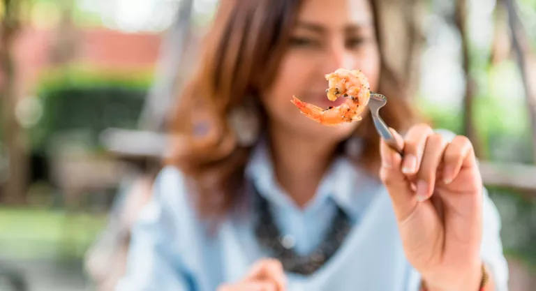 Mujer comiendo gambas