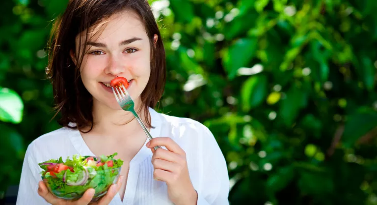 Adolescente tomando una ensalada