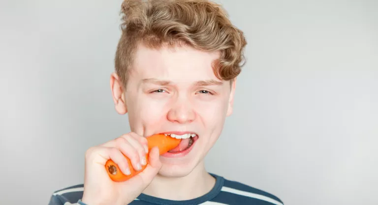 Adolescente tomando una zanahoria