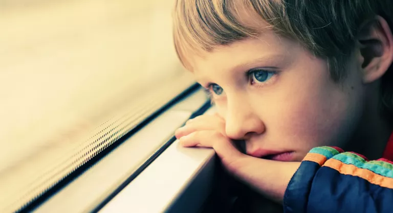 Niño autista mirando por la ventana