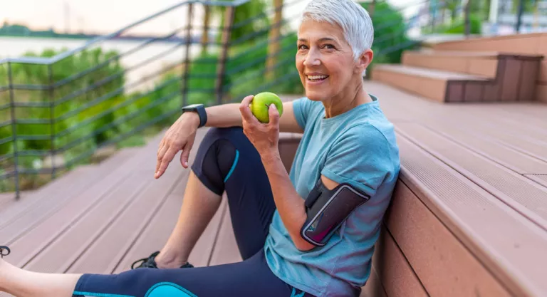 Mujer madura realizando deporte y comiendo una manzana