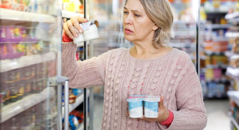 Mujer mirando la fecha de caducidad a unos yogures