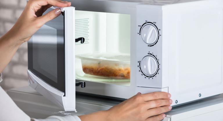 Mujer cocinando con el microondas