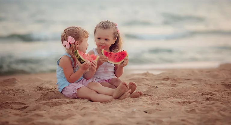 Niñas comiendo sandía en la playa