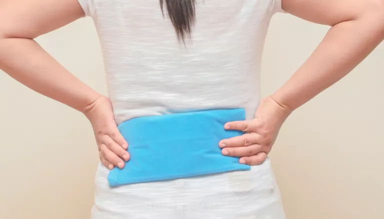 Persona con una bolsa de gel de calor puesta en la espalda