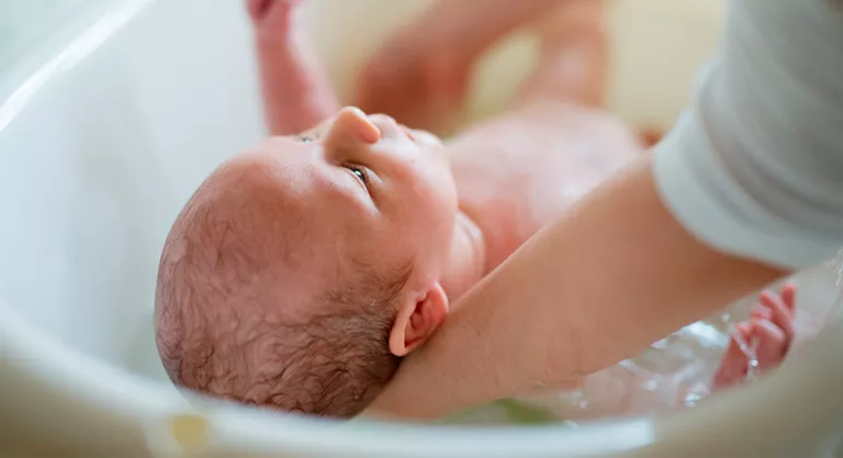 Madre bañando a su recién nacido de pocas semanas