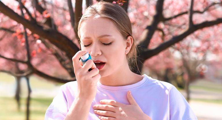 Mujer con alergia respiratoria usa inhalador para el asma