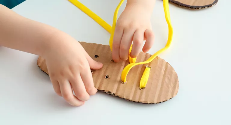 Niño ejerciendo su autonomía aprendiendo a atar cordones a los zapatos