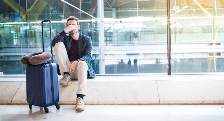 Hombre cansado en el aeropuerto debido al jet lag