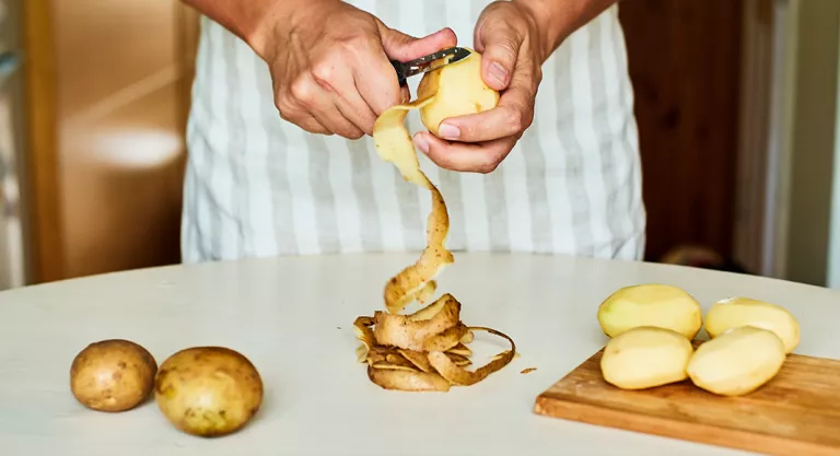 Mujer pelando patatas en la cocina