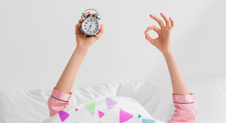 Mujer con despertador practica el sueño por ciclos