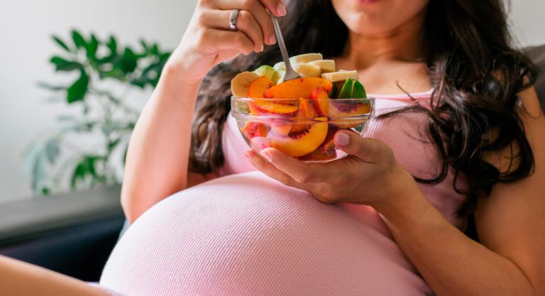 Embarazada comiendo frutas que aportan yodo