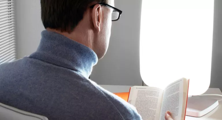 Hombre leyendo iluminado con una lámpara de luz diurna