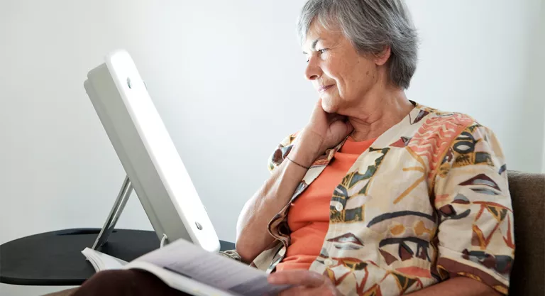 Senior woman with a daylight lamp