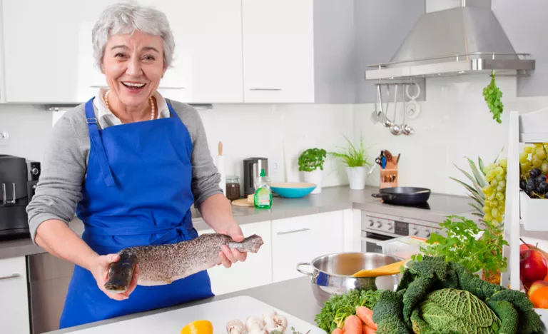 Mujer anciana cocinando pescado