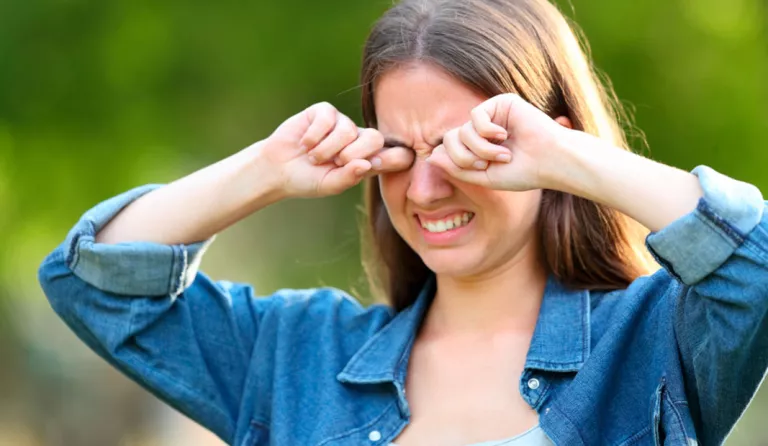 Mujer rascándose los ojos en un parque