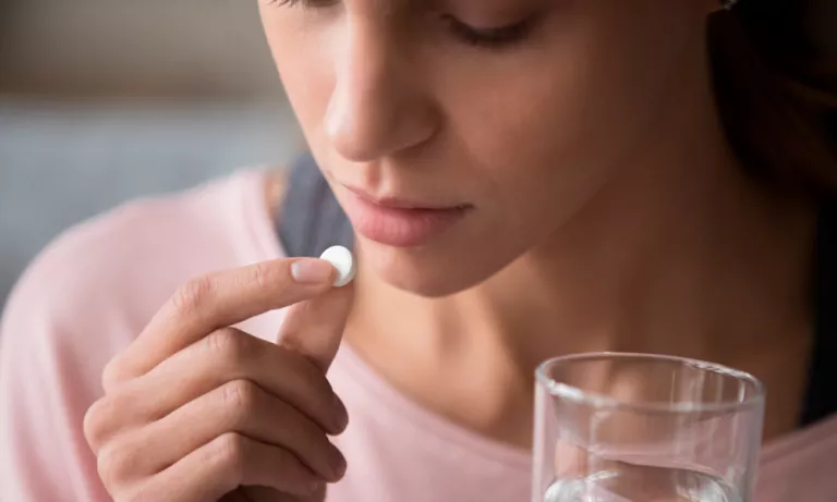 Woman taking a pill to treat a headache