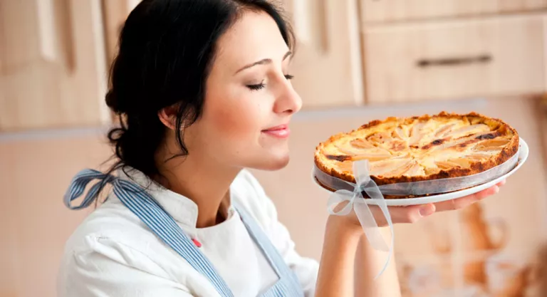 Mujer oliendo una tarta de manzana recién hecha