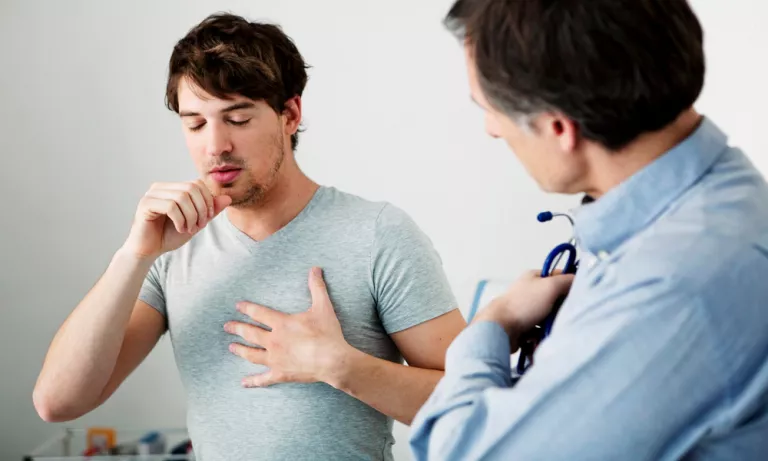 Joven describiendo al médico el dolor de pecho que padece