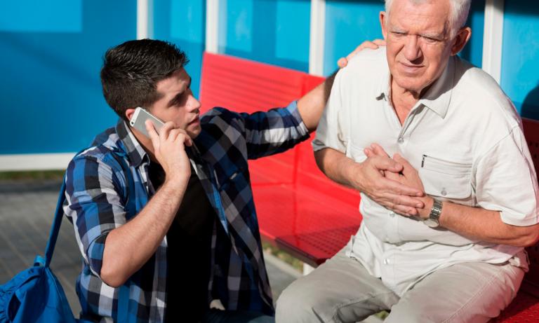 Joven avisando a los servicios médicos porque un anciano tiene dolor de pecho