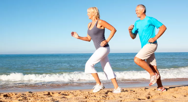 Pareja senior corriendo por la playa