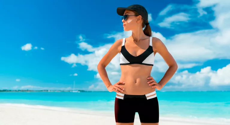 Mujer con gorra, gafas de solo y crema solar preparada para correr por la playa