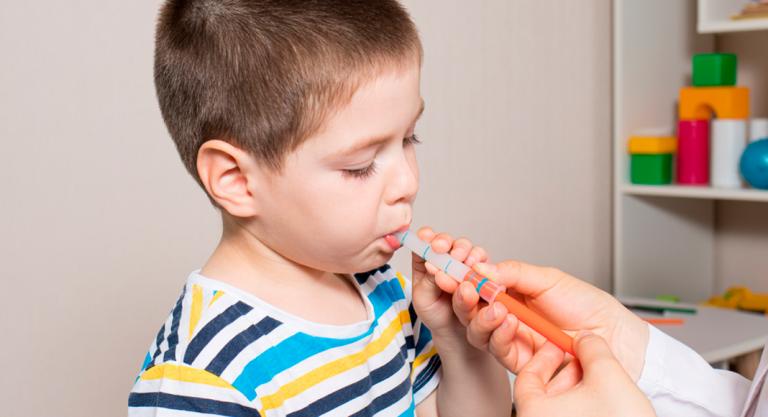 Niño tomando medicina con una jeringuilla