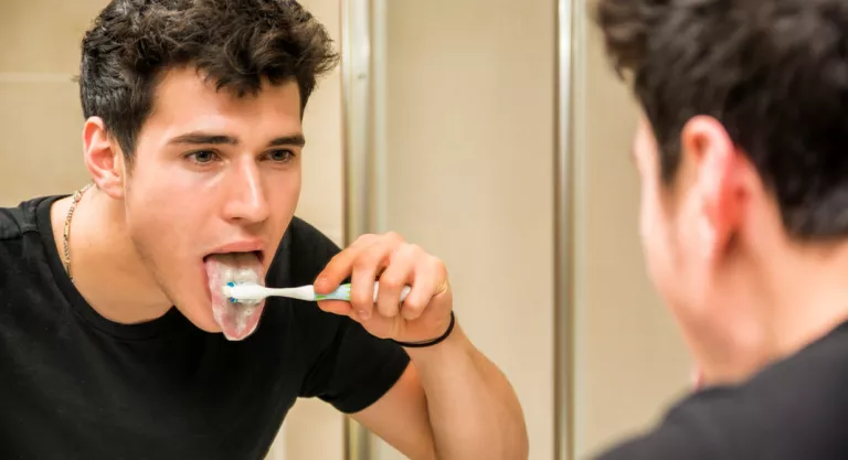 Chico joven cepillando su lengua