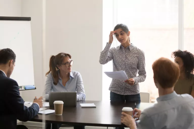 Mujer intentando hablar con dificultad ante sus compañeros de trabajo