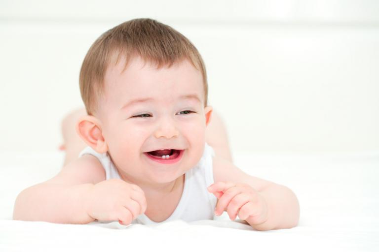 Bebé sonriendo mostrando sus dientes temporales